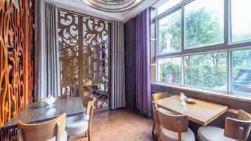 A dining area with wooden tables and chairs, a decorative screen, and a view through large windows.