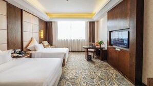 A hotel room with two beds, a television, a desk with a chair, and a patterned carpet. - Jia Lian Hotel (Daozhen)