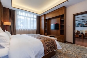 Habitación de hotel con una cama grande, un televisor montado en la pared y un cuadro en la pared contigua.