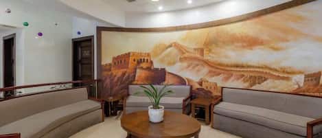 A lobby with a large mural, a round wooden table, and two sofas.