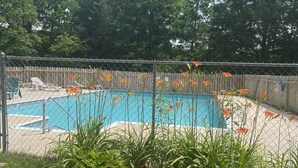 Patio trasero con piscina, rodeado por una cerca de madera y diversas plantas.