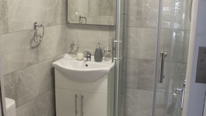 A bathroom with a toilet, sink, and glass-enclosed shower. - Charming Accommodation Close to Birmingham (West Bromwich)