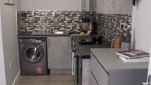 A compact kitchen with a washing machine, a sink, and a countertop with a book. - Charming Accommodation Close to Birmingham (West Bromwich)