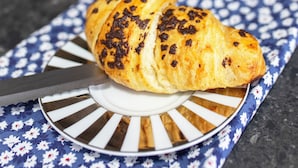 A croissant on a plate with a knife, a cup of coffee, and a coffee pot on a table. - Charming Accommodation Close to Birmingham (West Bromwich)