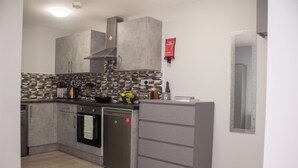 A modern kitchen with grey cabinets, a built-in oven, and a stainless steel dishwasher. - Charming Accommodation Close to Birmingham (West Bromwich)