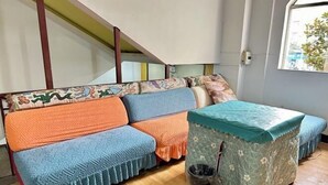 A room with a sofa set covered in patterned blankets, a small table with a green tablecloth, and a trash bin. - Duyun Jiayuan Hotel (Duyun)