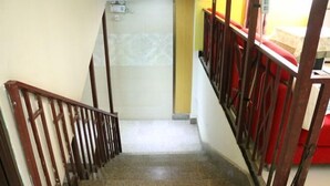 A staircase with a wooden handrail and red chairs on the upper landing. - Duyun Jiayuan Hotel (Duyun)