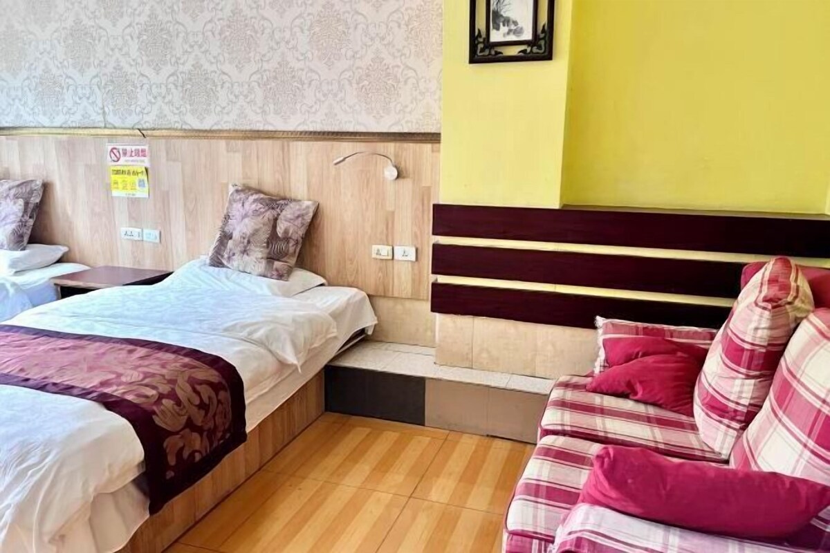 A hotel room with two beds, a sofa, and a wooden headboard.