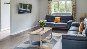 A modern living room with a sofa, a coffee table, and a TV mounted on the wall. - Kingfisher Lodge - UK40017 (Halwill Junction, near Beaworthy)