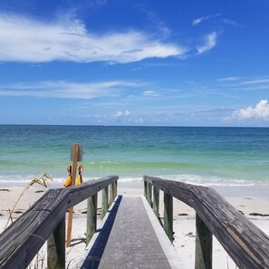 A wooden pier leading to a beach with clear turquoise water and a blue sky. - FALL IN LOVE! Gorgeous, colorful pool home mins from Anna Maria! Pet friendly! (Bradenton)