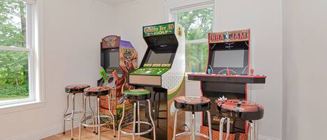 Une salle avec des jeux d’arcade et des tabourets.
