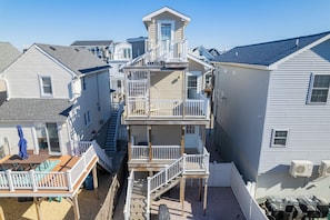 A multi-story residential building with a central staircase, balconies, and a deck area.