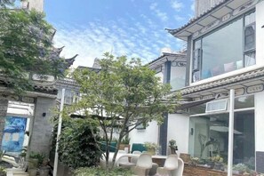 Un patio con arquitectura tradicional, que incluye un edificio con tejado de baldosas y un árbol.