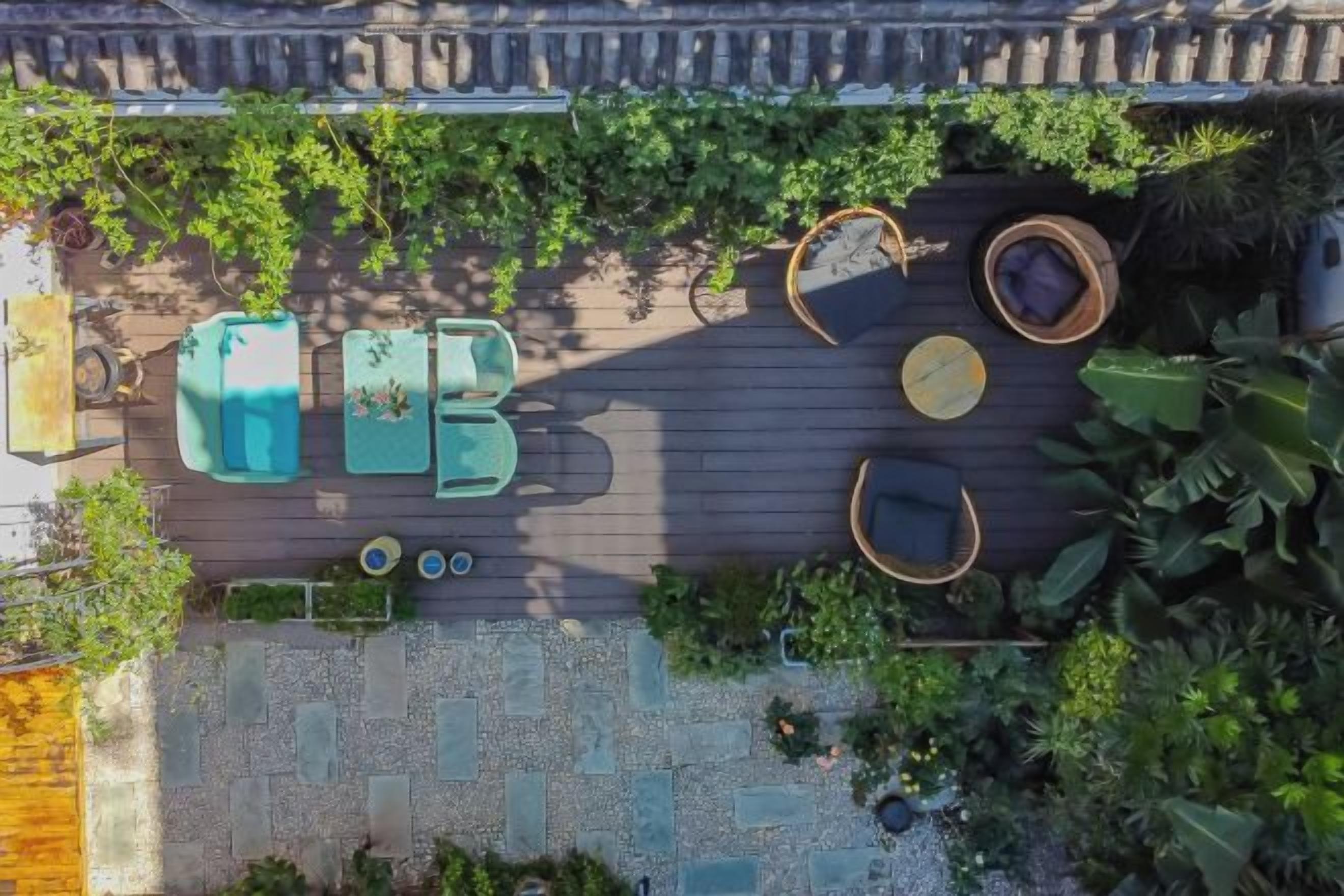 An aerial view of a rooftop garden with seating areas, planters, and a wooden deck.