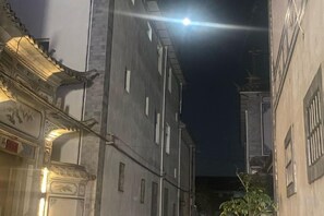 Un estrecho callejón con arquitectura tradicional, incluyendo un edificio con detalles ornamentales y un cartel.