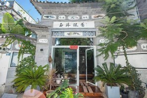 A traditional Chinese gate with a sign, surrounded by potted plants. - Erduobian Inn (Dali City)