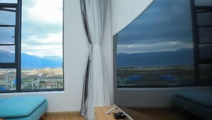 A room with a large window, a wooden bench, a blue sofa, and a curtain. - Erduobian Inn (Dali City)