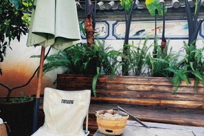 A seating area with a chair labeled 'TANXING,' a wooden bench, and a table with a bowl and chopsticks. - Erduobian Inn (Dali City)