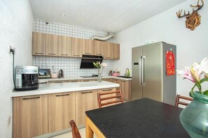 A compact kitchen with wooden cabinets, a refrigerator, and a coffee maker. - Erduobian Inn (Dali City)