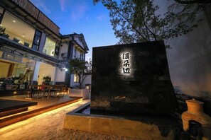 A stone monument with Chinese characters, a building with large windows, and outdoor seating. - Erduobian Inn (Dali City)