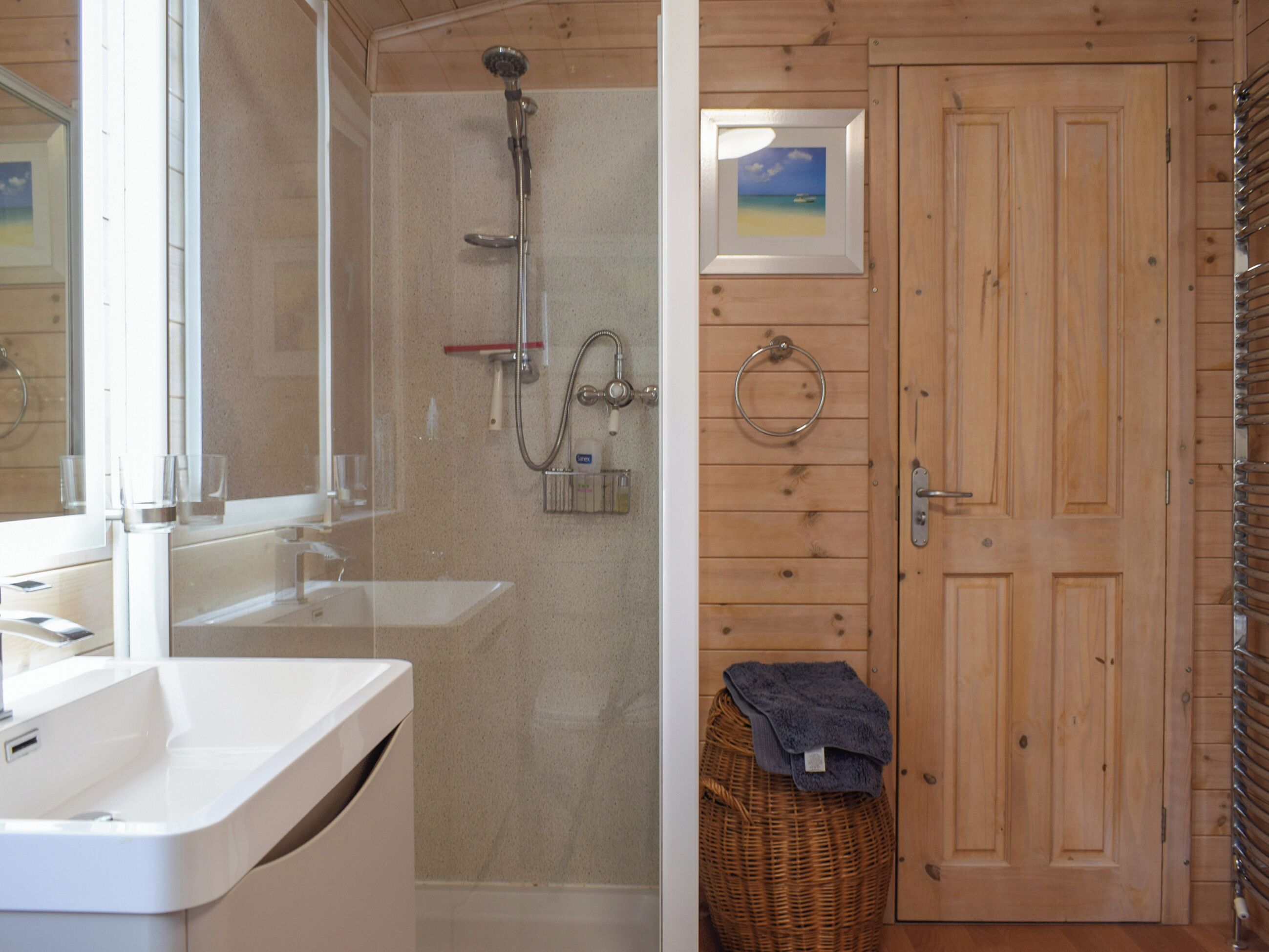 A bathroom with a shower, sink, and wooden walls.