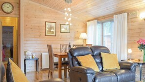 A cozy living room with a leather sofa, wooden dining table, and a glass coffee table. - 2 bedroom accommodation in Bridgnorth (Bridgnorth)