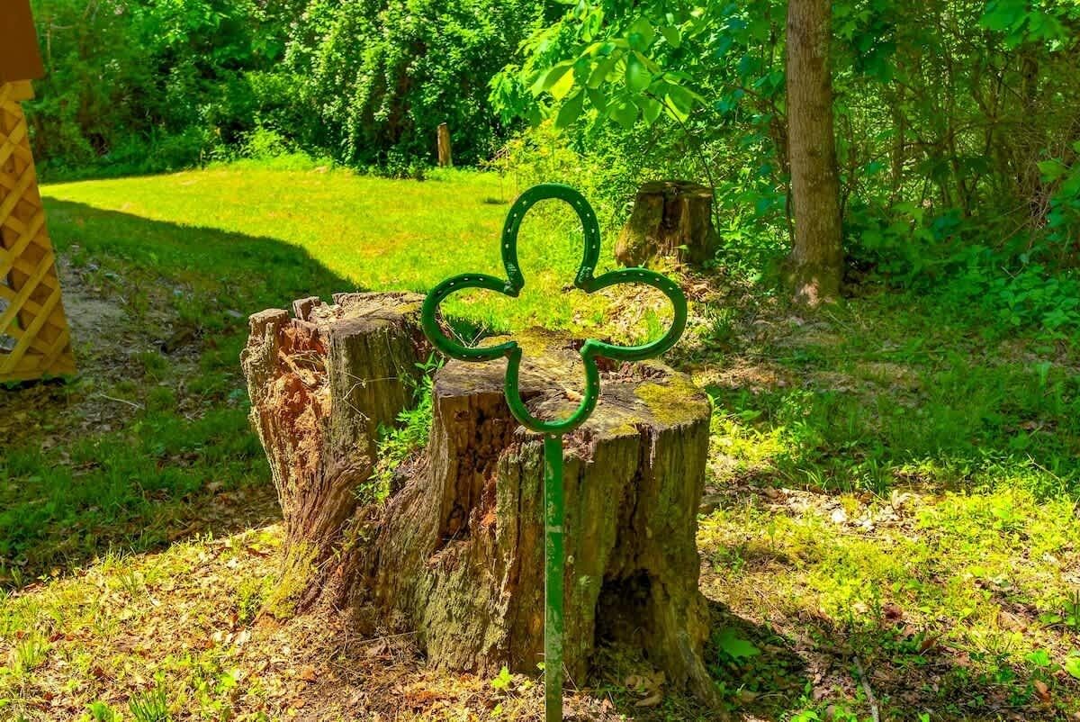 A tree stump with a green clover-shaped sign.