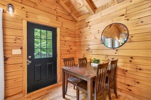 Un intérieur en bois avec une porte noire, un miroir rond et une table à manger avec des chaises.