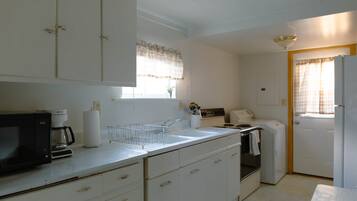 A compact kitchen with white cabinets, a microwave, a sink, and a refrigerator.
