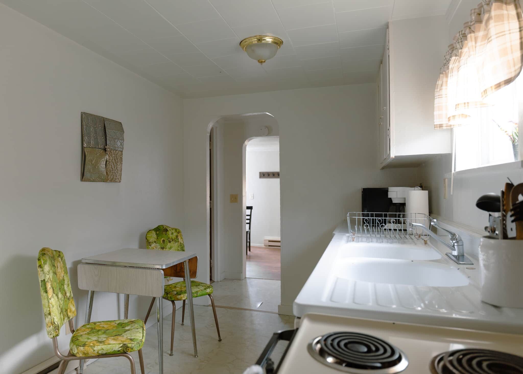 A kitchen with a stove, a sink, and a dining area with a table and chairs.