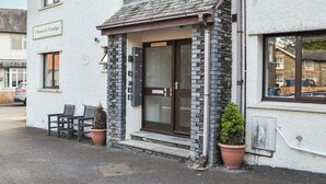 Een gebouw met een gevel van steen, een houten deur en een bord met de tekst 'Chaucer Lodge'.