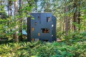 A modern, multi-story building surrounded by dense forest.