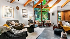 A modern living room with leather sofas, a round coffee table, and wooden beams on the ceiling.