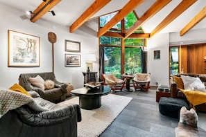 A modern living room with leather sofas, a round coffee table, and wooden beams on the ceiling.