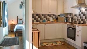 Een kleine keuken met witte kastjes, een betegelde achterwand en een moderne kookplaat.