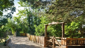 Een grindpad dat leidt naar een houten poort in een bebost gebied.