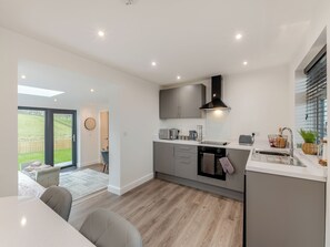 A modern kitchen with grey cabinets, a black range hood, and a built-in oven. - The Bunker - UK40225 (Bardon Mill, nr Hexham)
