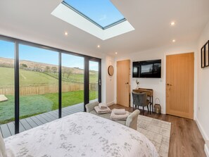 A bedroom with a skylight, a TV, a desk, and a view of a grassy field. - The Bunker - UK40225 (Bardon Mill, nr Hexham)
