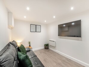 A modern living room with a grey sofa, a flat-screen TV, framed certificates on the wall, and a small table with a plant. - The Bunker - UK40225 (Bardon Mill, nr Hexham)