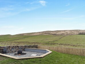 A fenced outdoor area with a stone wall, a fire pit, and a seating area. - The Bunker - UK40225 (Bardon Mill, nr Hexham)
