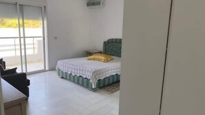 Un dormitorio con cama, mesita de noche y ventana con persianas.