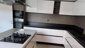 Una cocina moderna con armarios blancos, encimera negra y estufa a gas.