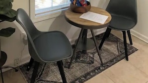 A small room with a window, two chairs, a table with snacks, and a plant. - “Mint City w Soul...” 2BR 5 min to Stadium & UMMC! (Jackson)