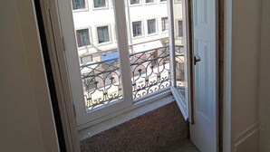 Une pièce dotée d’une grande fenêtre donnant sur un balcon agrémenté d’une rambarde en métal.