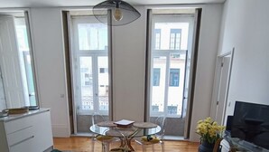 Un salon moderne avec un canapé vert, une table à manger ronde et un téléviseur.