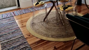 Un espace repas comprenant une table ronde en verre, des chaises transparentes et un tapis tissé.