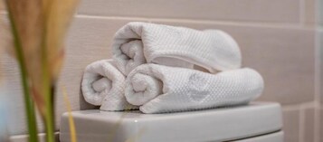 A stack of white towels on a white surface, likely in a bathroom setting.