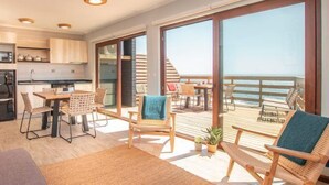Un interior moderno con cocina, comedor y un balcón con vistas al mar.