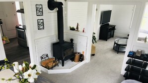Een gezellige woonkamer met een open haard, een televisie en een eethoek met een bloevas.