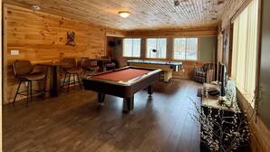 Un intérieur en bois comprenant une table de billard, des chaises et une table de jeu de billard.